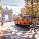 Famous vintage tram in the centre of the Old Town of Milan in the sunny day, Lombardia, Italy. Arch of Peace, or Arco della Pace on the background.