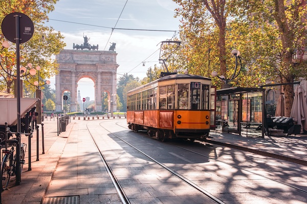 Famous vintage tram in the centre of the Old Town of Milan in the sunny day, Lombardia, Italy. Arch of Peace, or Arco della Pace on the background.